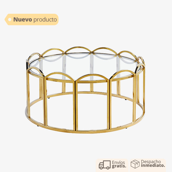 Mesa de centro dorada con base ondulada y cubierta de vidrio.