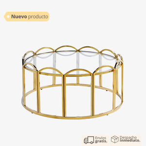 Mesa de centro dorada con base ondulada y cubierta de vidrio.