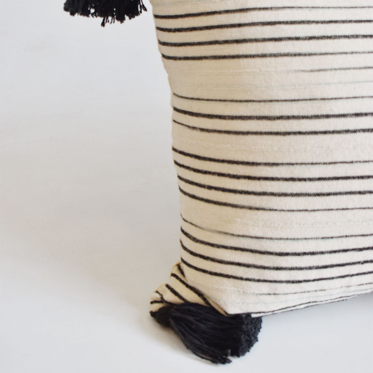 cojín rectangular beige con rayas negras y pompones relleno de pluma vertihome