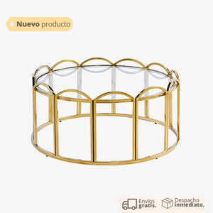 Mesa de centro dorada con base ondulada y cubierta de vidrio.