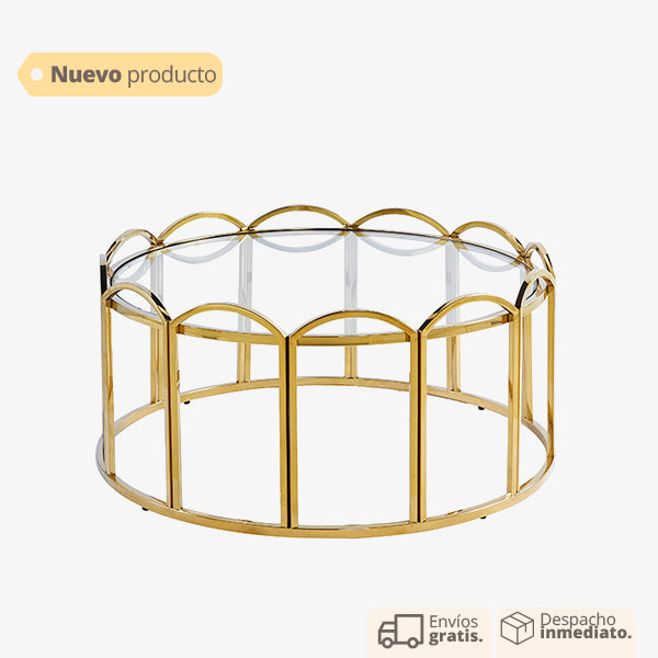 Mesa de centro dorada con base ondulada y cubierta de vidrio.