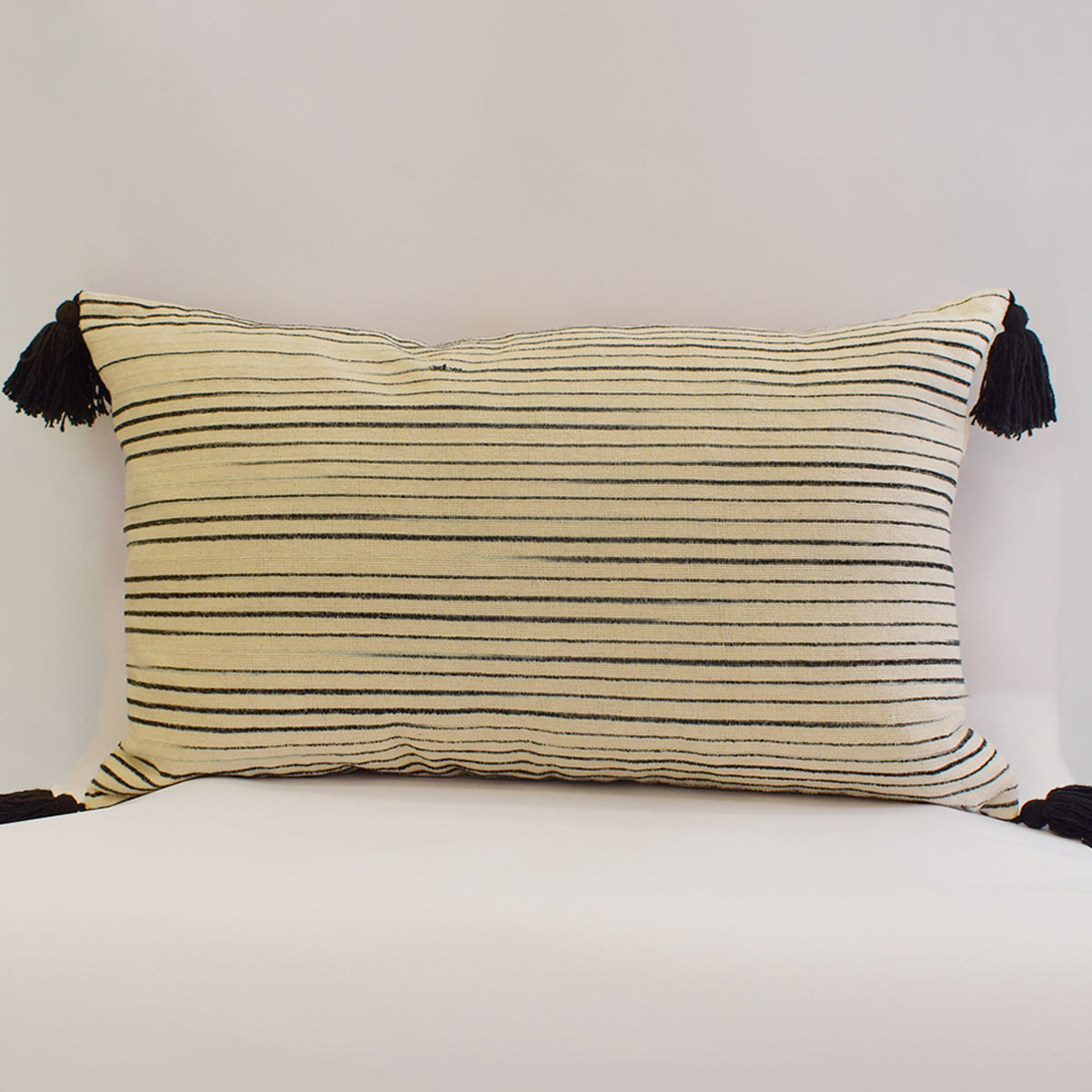 cojín rectangular beige con rayas negras y pompones relleno de pluma vertihome