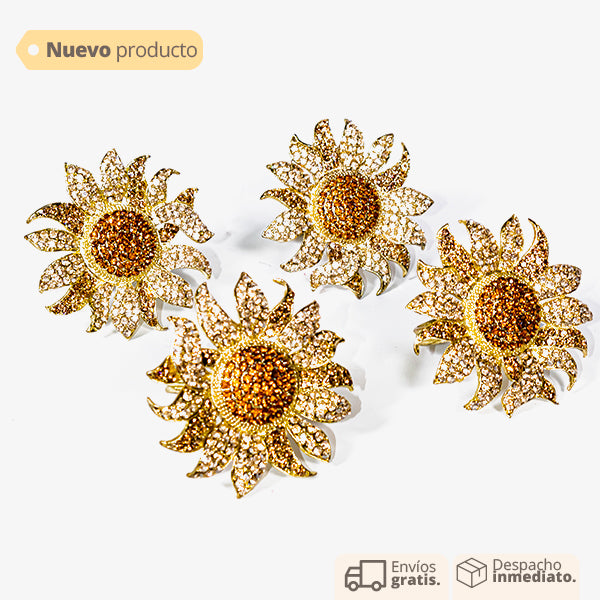 Set de servilleteros en forma de flor dorada con pedrería, diseño elegante y tropical para decoración de mesa.